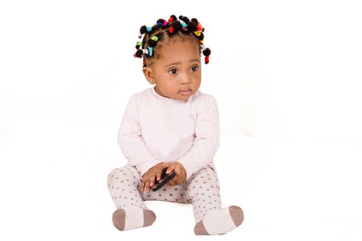 Pretty baby sitting and playing with a cell phone on white background