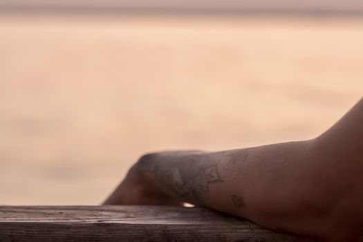 a good looking partial closeup shoot to tattooed girl arm - blurry sea as background. photo has taken at izmir/turkey.