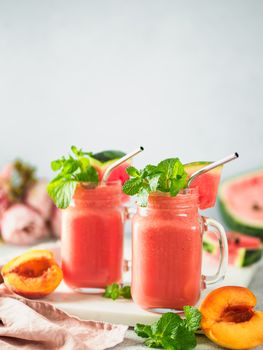 Freshly Blended Watermelon and Peach Smoothies in mason jar and metal straw. Copy space for text or design. Vertical.