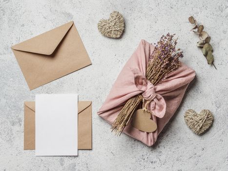 Zero waste Valentine's Day concept and mock up. Eco-friendly gift cloth wrapping in Furoshiki style, craft paper envelope, empty gift or greetings card, copy space