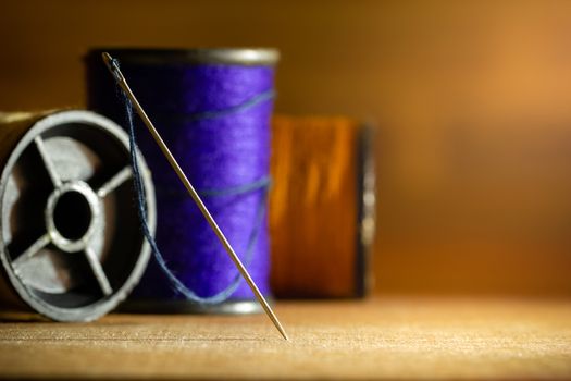 Needle and threads on wooden table. Closeup and copy space for text. Concept of tailor or Designer.