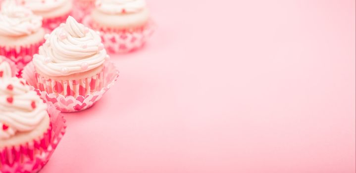 Valentine day love cupcakes decorated with cream and hearts on pink background with copy space for text