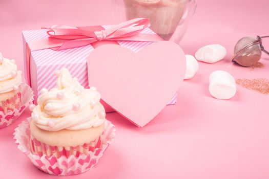 Valentine day love cupcake decorated with cream gift and hearts on pink background with copy space for text