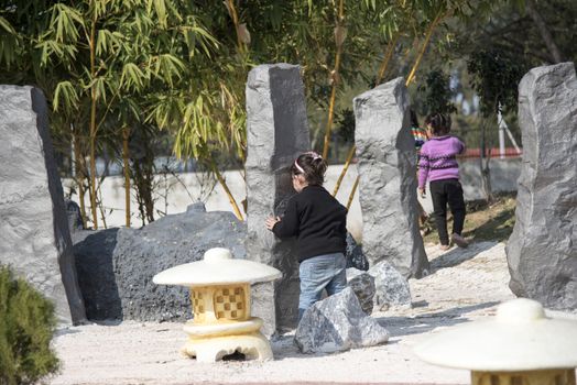 Children playing hide and seek outdoors in Japanese Garden, Chandigarh, India.