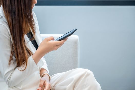 Business women wear white clothes glad to play mobile phone in a white background