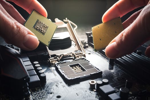 Hand shows different gestures. Two CPUs against the background of the motherboard are fingered. The choice of processor, the advantage of the brand and technology.