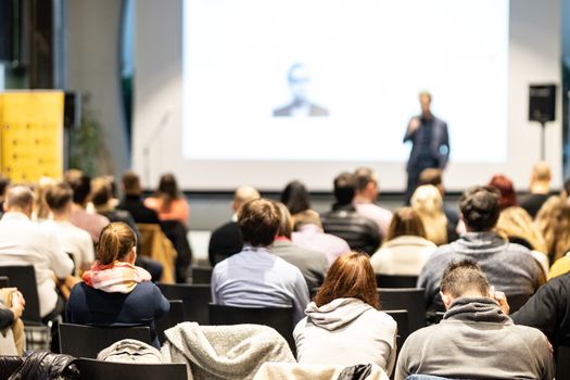 Speaker giving a talk in conference hall at business event. Audience at the conference hall. Business and Entrepreneurship concept. Focus on unrecognizable people in audience.