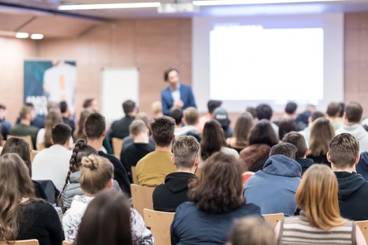 Speaker giving a talk in conference hall at business event. Audience at the conference hall. Business and Entrepreneurship concept. Focus on unrecognizable people in audience.