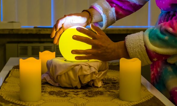 fortune teller moving hands around a lighted sphere, traditional spirituality and witchcraft