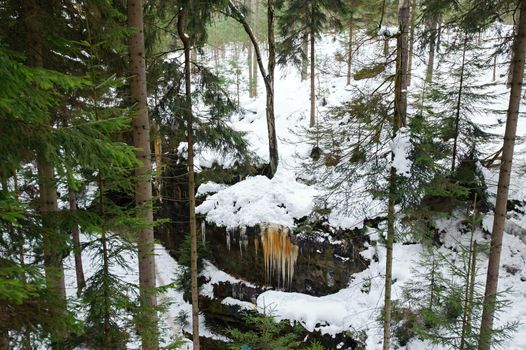 Frozen waterfalls on the rock, orange colored and snow