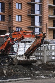 Orange excavator works on construction site with a gravel and carry it fromone place to another. Heavy industry. Construction of a building