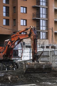 Orange excavator works on construction site with a gravel and carry it fromone place to another. Heavy industry. Construction of a building