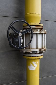 Yellow gate valve on the pipe allows to distribute natural gas and turn it off if necessary. A flange is installed on the pipeline next to the crane. It s located near home