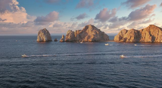 The rocks at Cabo San Lucas at Dawn with fishing boats heading out for the day