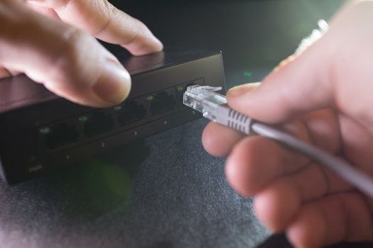 Close-up Hand holding ethernet cable on network switches background