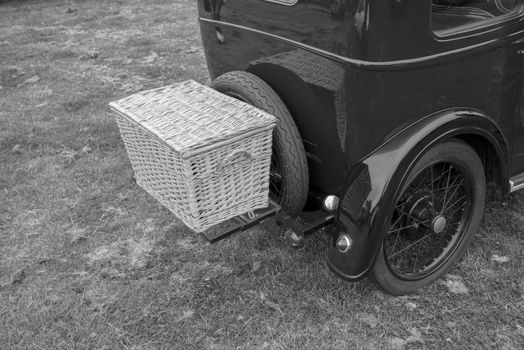 old luxury car with large mudguards and a basket on the back in black and white