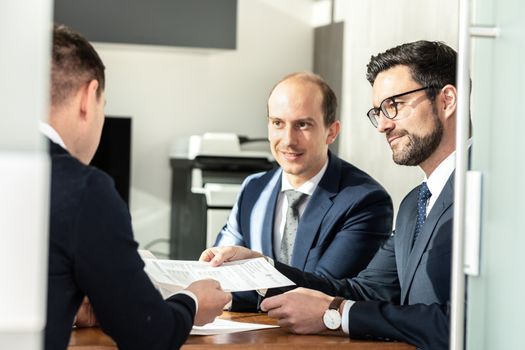 Team of confident successful business people reviewing and signing a contract to seal the deal at business meeting in modern corporate office. Business and entrepreneurship concept.