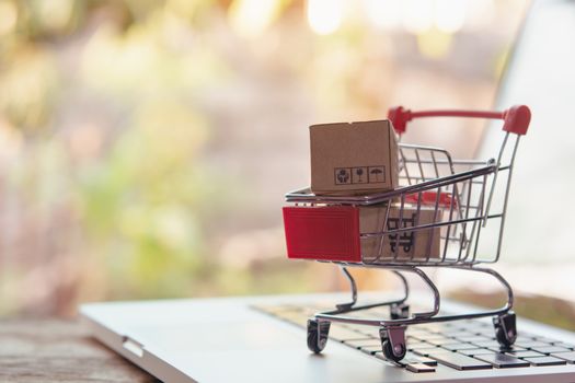 Shopping online concept - Parcel or Paper cartons with a shopping cart logo in a trolley on a laptop keyboard. Shopping service on The online web. offers home delivery.

