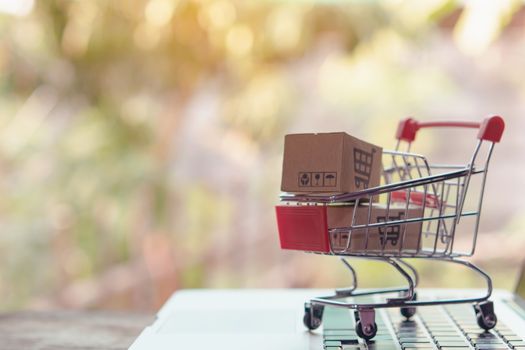 Shopping online concept - Parcel or Paper cartons with a shopping cart logo in a trolley on a laptop keyboard. Shopping service on The online web. offers home delivery.

