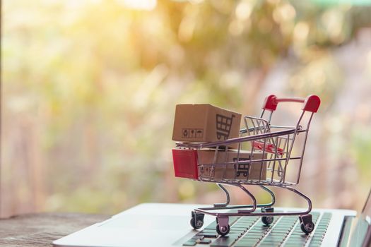 Shopping online concept - Parcel or Paper cartons with a shopping cart logo in a trolley on a laptop keyboard. Shopping service on The online web. offers home delivery.

