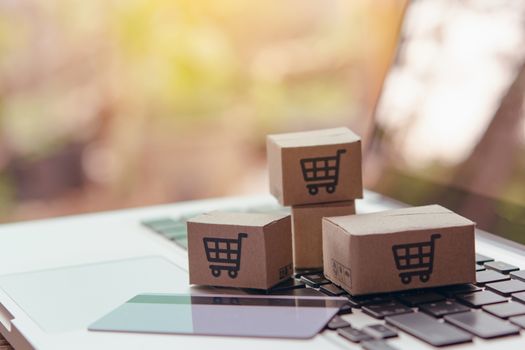 Online shopping - Paper cartons or parcel with a shopping cart logo and credit card on a laptop keyboard. Shopping service on The online web and offers home delivery.

