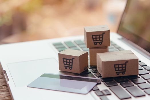 Online shopping - Paper cartons or parcel with a shopping cart logo and credit card on a laptop keyboard. Shopping service on The online web and offers home delivery.

