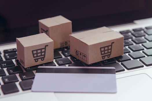 Online shopping - Paper cartons or parcel with a shopping cart logo and credit card on a laptop keyboard. Shopping service on The online web and offers home delivery.

