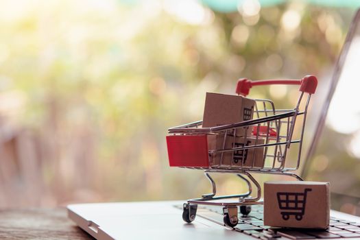 Shopping online concept - Parcel or Paper cartons with a shopping cart logo in a trolley on a laptop keyboard. Shopping service on The online web. offers home delivery.

