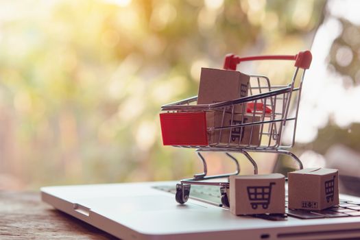 Shopping online concept - Parcel or Paper cartons with a shopping cart logo in a trolley on a laptop keyboard. Shopping service on The online web. offers home delivery.

