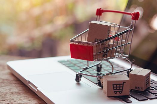 Shopping online concept - Parcel or Paper cartons with a shopping cart logo in a trolley on a laptop keyboard. Shopping service on The online web. offers home delivery.

