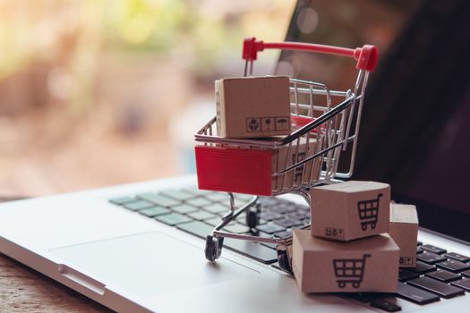 Shopping online concept - Parcel or Paper cartons with a shopping cart logo in a trolley on a laptop keyboard. Shopping service on The online web. offers home delivery.

