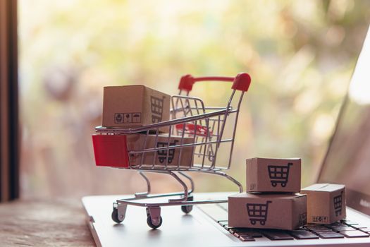 Shopping online concept - Parcel or Paper cartons with a shopping cart logo in a trolley on a laptop keyboard. Shopping service on The online web. offers home delivery.

