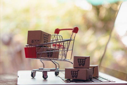 Shopping online concept - Parcel or Paper cartons with a shopping cart logo in a trolley on a laptop keyboard. Shopping service on The online web. offers home delivery.

