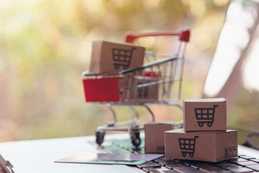 Shopping online concept - Parcel or Paper cartons with a shopping cart logo in a trolley on a laptop keyboard. Shopping service on The online web. offers home delivery.

