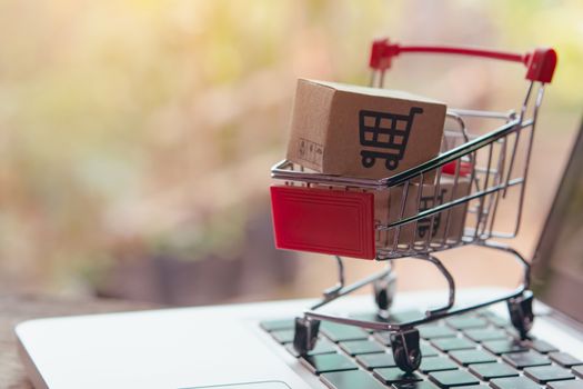 Shopping online concept - Parcel or Paper cartons with a shopping cart logo in a trolley on a laptop keyboard. Shopping service on The online web. offers home delivery.

