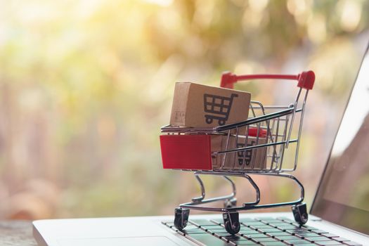 Shopping online concept - Parcel or Paper cartons with a shopping cart logo in a trolley on a laptop keyboard. Shopping service on The online web. offers home delivery.

