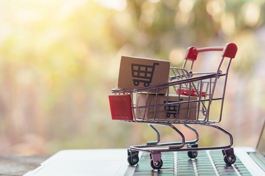 Shopping online concept - Parcel or Paper cartons with a shopping cart logo in a trolley on a laptop keyboard. Shopping service on The online web. offers home delivery.

