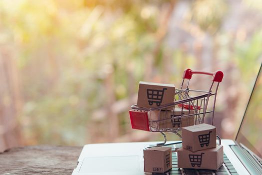 Shopping online concept - Parcel or Paper cartons with a shopping cart logo in a trolley on a laptop keyboard. Shopping service on The online web. offers home delivery.

