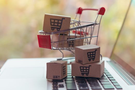 Shopping online concept - Parcel or Paper cartons with a shopping cart logo in a trolley on a laptop keyboard. Shopping service on The online web. offers home delivery.

