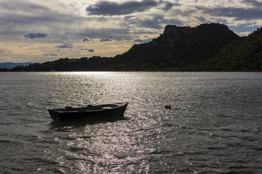 Small boat in Vouliagmeni lake near Loutraki at sunset, Greece