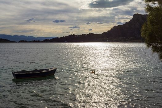 Small boat in Vouliagmeni lake near Loutraki at sunset, Greece