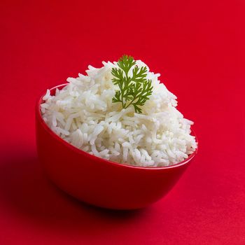 Cooked plain white basmati rice in a red bowl on red background