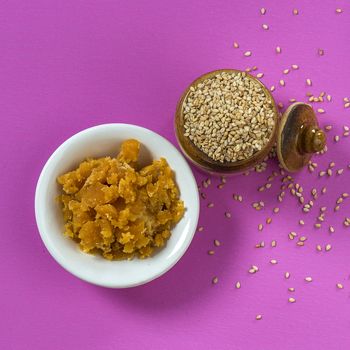 Sesame Seeds in clay pot with Jaggery in bowl on pink background