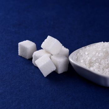 Sugar Cubes with Sugar in white plate on blue background