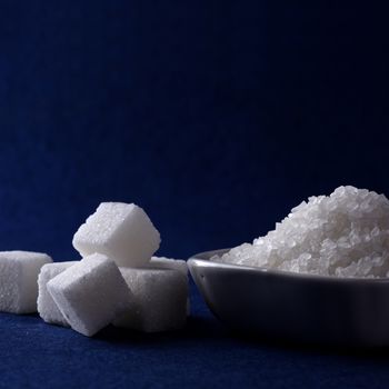 Sugar Cubes with Sugar in white plate on blue background