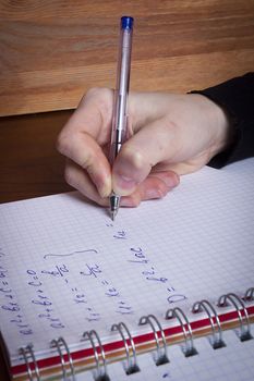 Hand writes math formulas in a notebook