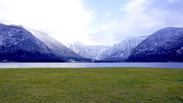 panorama of Hallstatt lake and green grass field outdoor dreamscape with snow mountain background in Austria in Austrian alps