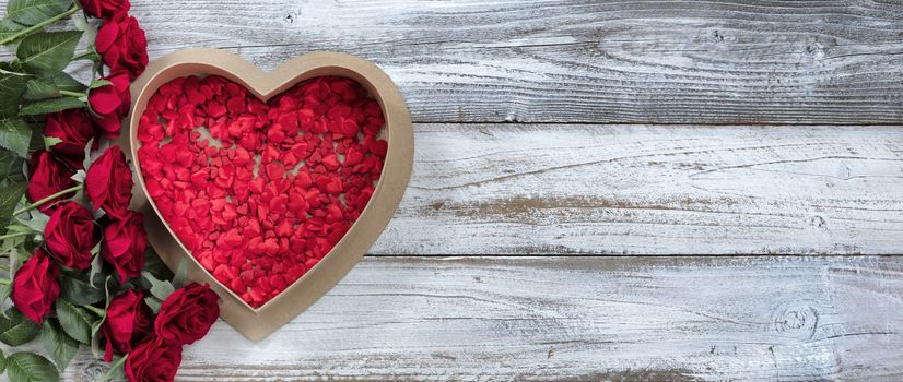 Happy Valentines Day gift box filled with tiny hearts and red roses on white rustic wood    