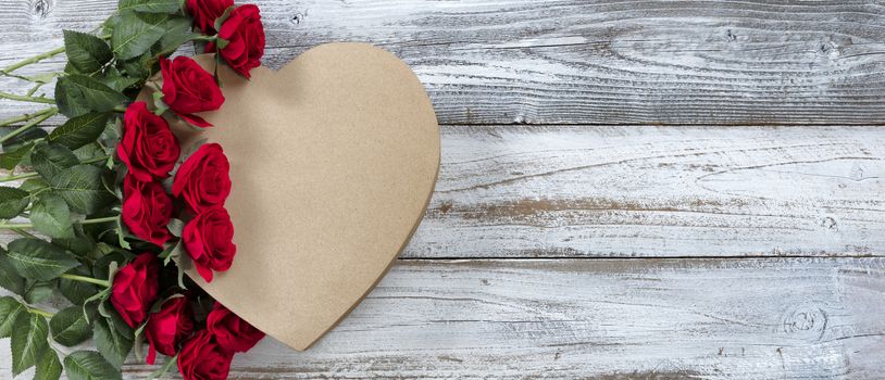 Happy Valentines Day with red roses on top of a heart shaped gift box with  white rustic wooden background   