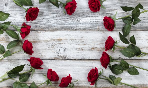 Happy Valentines Day with red roses forming heart outline on white rustic wood  